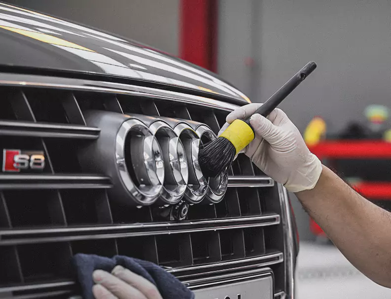 A Man Holding the Brush and cleaning the Audi Car Logo